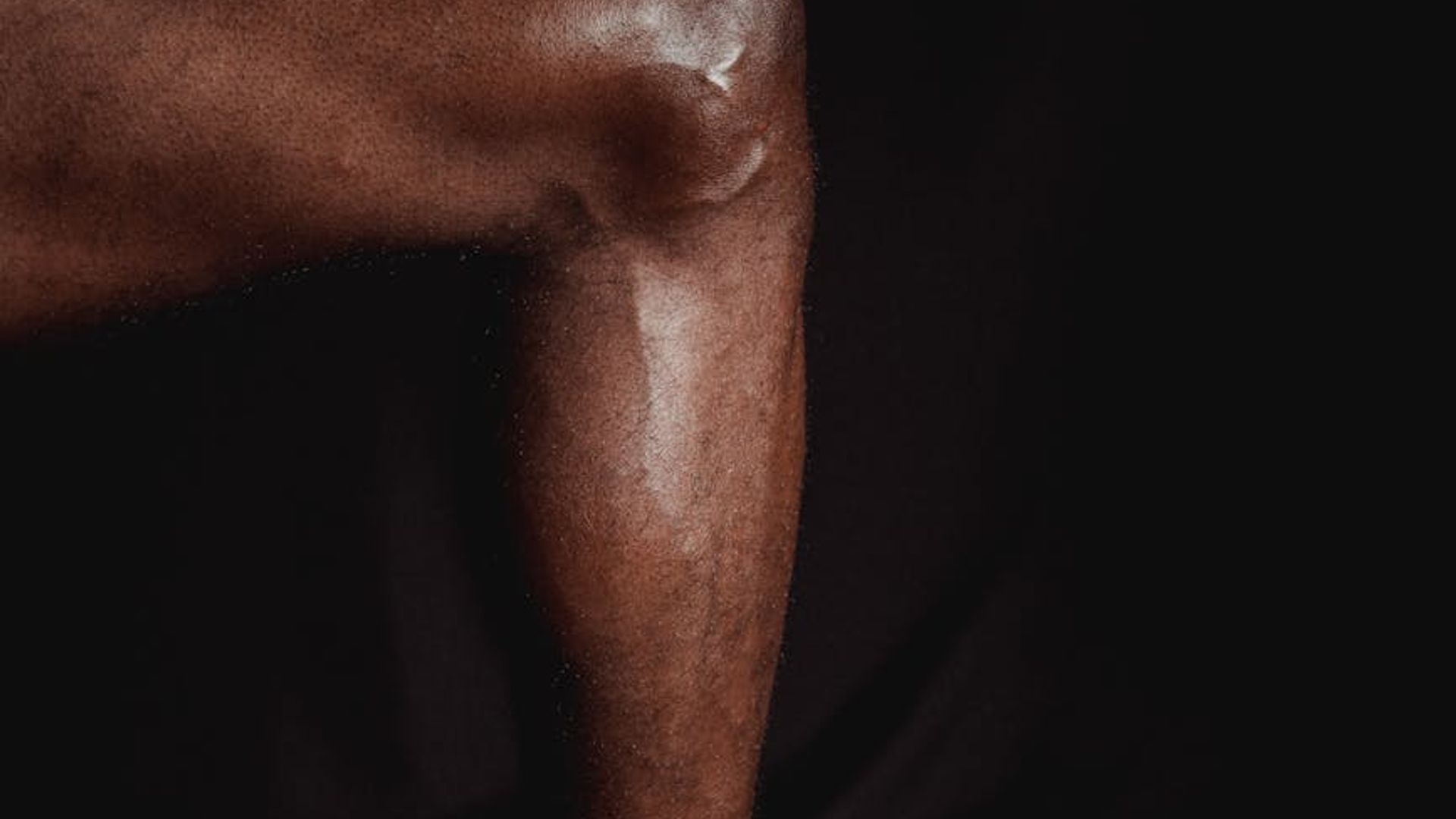 Man performing a controlled strength exercise in a minimalist dark gym.